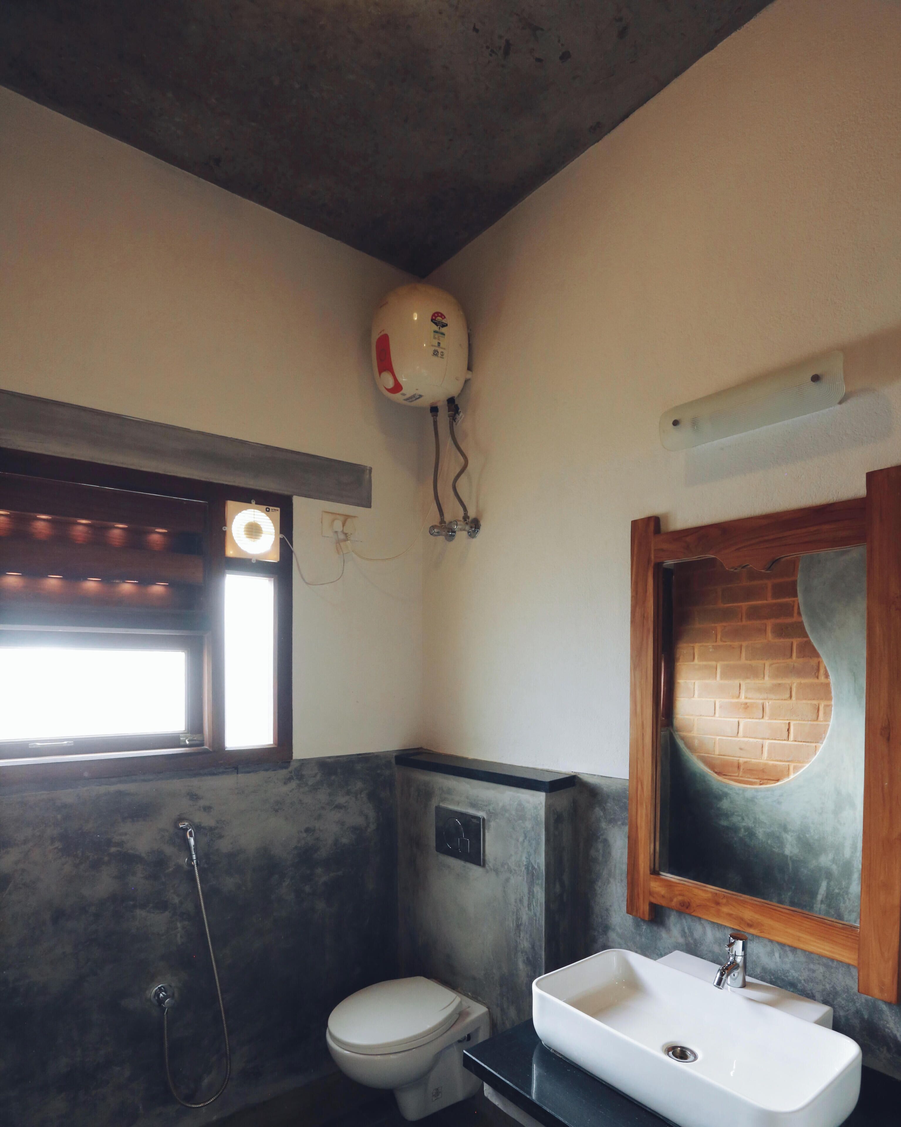 Une salle de bain comprenant des toilettes, un lavabo, une douche et une fenêtre avec un luminaire.