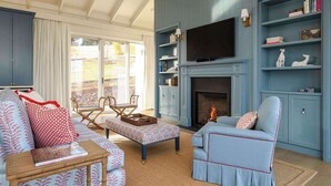 Una sala de estar con chimenea, televisor y estantería.