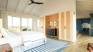 Un dormitorio con una cama grande, vistas al campo, un aparador de madera y una zona de cocina.