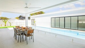 A modern outdoor dining area with a pool, white walls, and a clear view of the sky. - 57 Tomaree Road House - Pool, Air-con, Wi-fi, Boat Parking (Shoal Bay)
