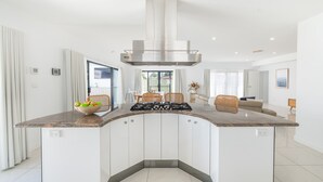 Una cucina moderna con isola centrale, mobili a scomparsa e cappa aspirante in acciaio inossidabile.
