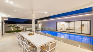 A modern outdoor dining area with a pool, white furniture, and a view of the interior. - 57 Tomaree Road Complex - House and Cabana with Pool, Linen, Air-con, Wi-fi, Boat Parking (Shoal Bay)