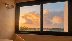 Ein Fenster mit Blick auf einen Sonnenuntergang über einer Landschaft.