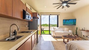 Eine moderne Küche mit integriertem Mikrowellenherd, Deckenventilator und einem großen Schiebeglastür, die auf einen Balkon mit einem weißen Sofa und einem Fernseher führt.