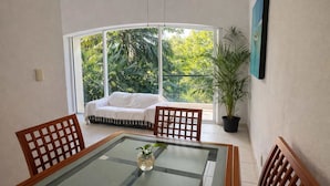 A sunlit room with a glass table, two wooden chairs, a white sofa, and a potted plant. - Pool + Jacuzzi Villa • Walk to Beach • Sleeps 16 (Puerto Aventuras)