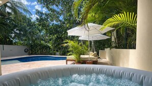 A hot tub surrounded by a pool, with a lounge area and tropical plants. - Pool + Jacuzzi Villa • Walk to Beach • Sleeps 16 (Puerto Aventuras)