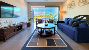 Uma sala de estar moderna com uma mesa de centro redonda, sofá azul e um ventilador de teto.
