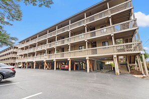 A multi-story hotel with balconies and a covered parking area. - Steps to the Beach, Close to It All — Shipwatch II 101K (Myrtle Beach)