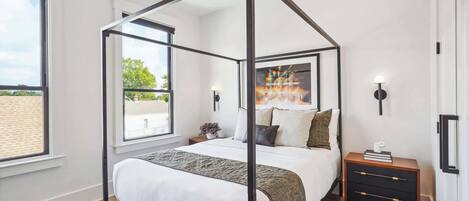 Een hemelbed met uitzicht op de omgeving, een nachtkastje met een boek, en een nachtkastje met een lamp.