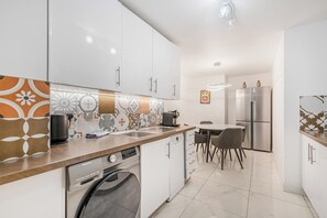 A modern kitchen with white cabinets, a dishwasher, a coffee maker, and a refrigerator. - Modern 2 bed in brilliant St Georges Wharf - Pass the Keys (London)