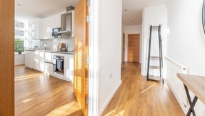 Une cuisine moderne avec des armoires blanches, un plan de travail en bois et un four encastré.