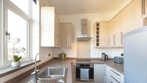 A modern kitchen with a stainless steel sink, a built-in oven, and a window with a plant. - A beautiful 2-bed mansion-block flat in Putney - Pass the Keys (London)