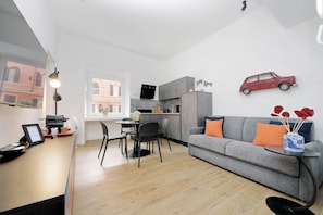 A modern living space with a dining area, kitchenette, and a sofa with cushions. - Ricky Bijoux by Domus&Dimore (Rome)