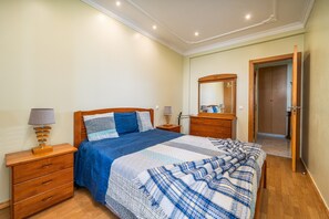 A bedroom with a bed, wooden nightstands, a dresser, a mirror, and a door leading to another room. - Apartment 'Belmar' with Sea View, Wi-Fi and Air Conditioning (Armação de Pêra)