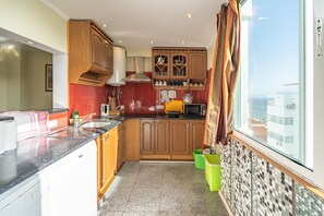A kitchen with wooden cabinets, a microwave, and a window with a view. - Apartment 'Belmar' with Sea View, Wi-Fi and Air Conditioning (Armação de Pêra)