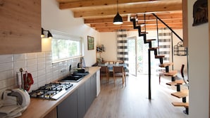 A modern kitchen with wooden beams, a dining area, and a staircase. - House With Private Garden and Sauna (Parchowo)