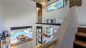 Een modern interieur met een wenteltrap, uitzicht op een zwembad en een eethoek.