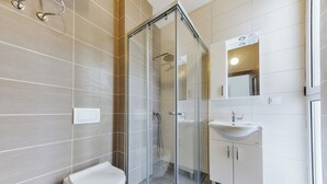 Ein modernes Badezimmer mit Duschkabine aus Glas, Toilette und Waschbecken mit Spiegel.