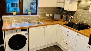 A compact kitchen with a washing machine, a sink, and a microwave.