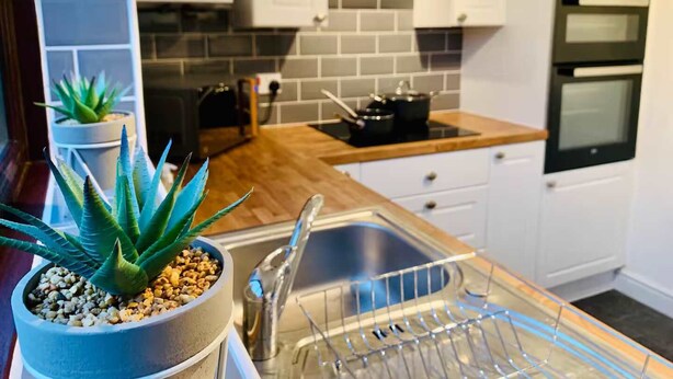 A modern kitchen with white cabinets, a stainless steel sink, and a black oven.