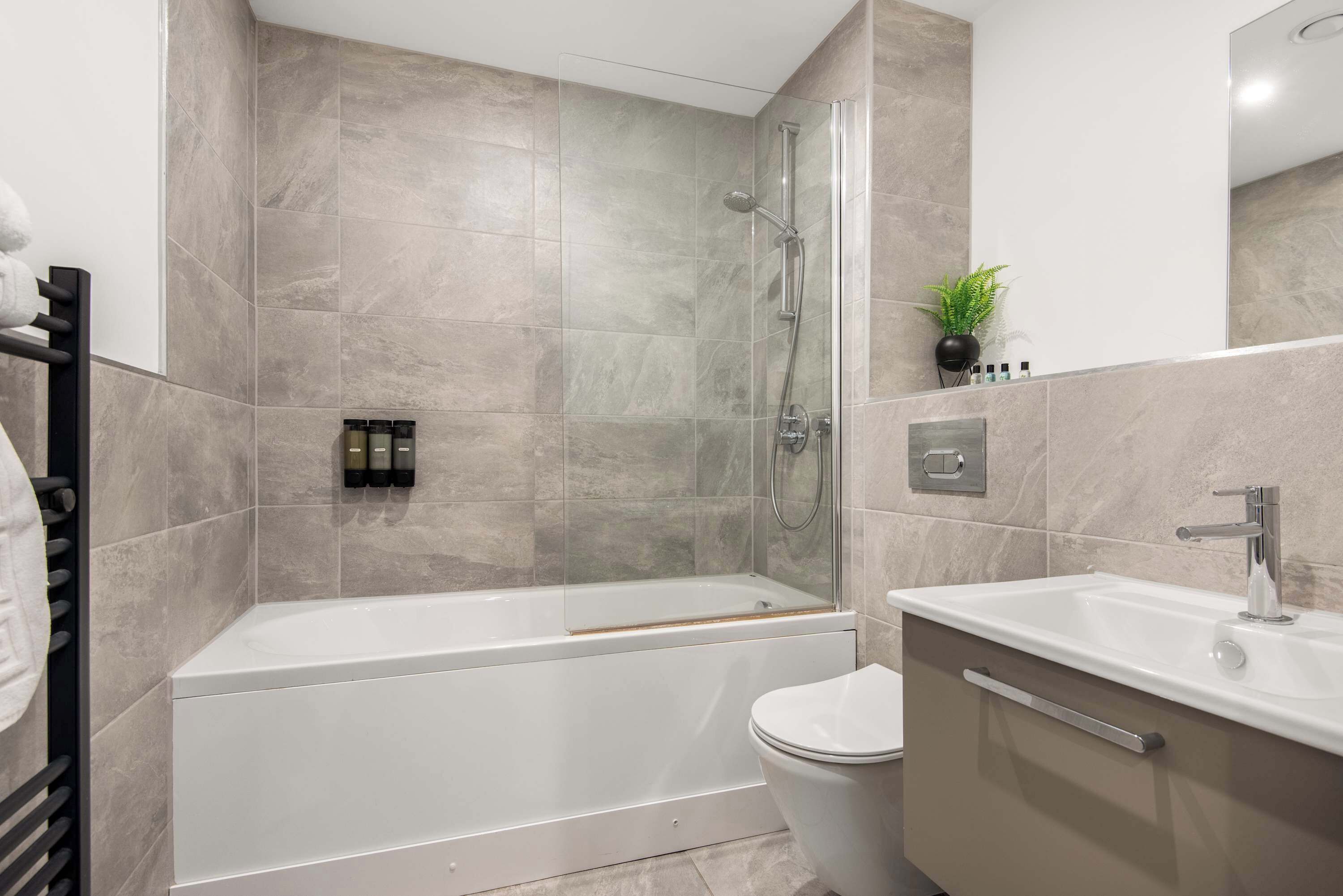 A modern bathroom with a bathtub, shower, toilet, and sink.