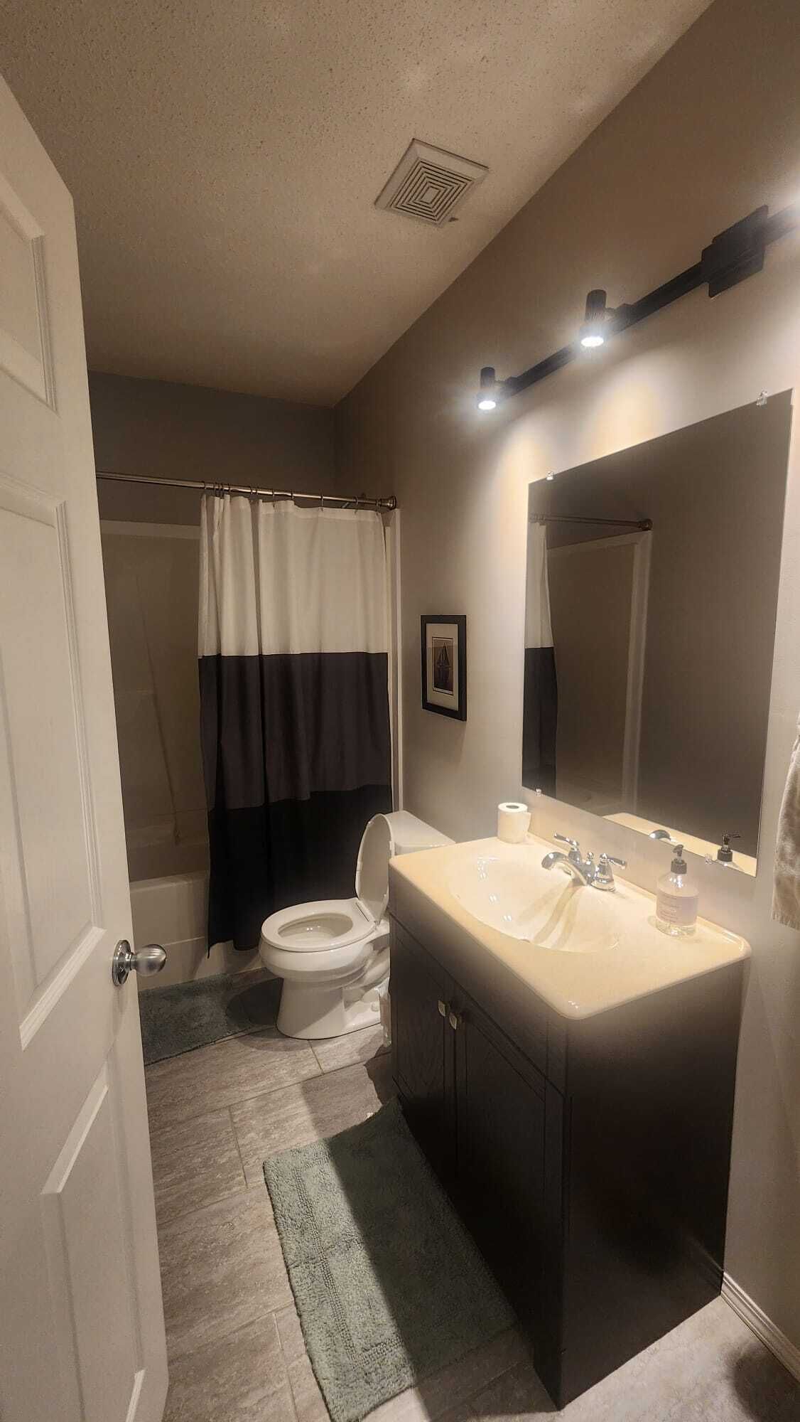 Un baño con inodoro, lavamanos y cortina de ducha.