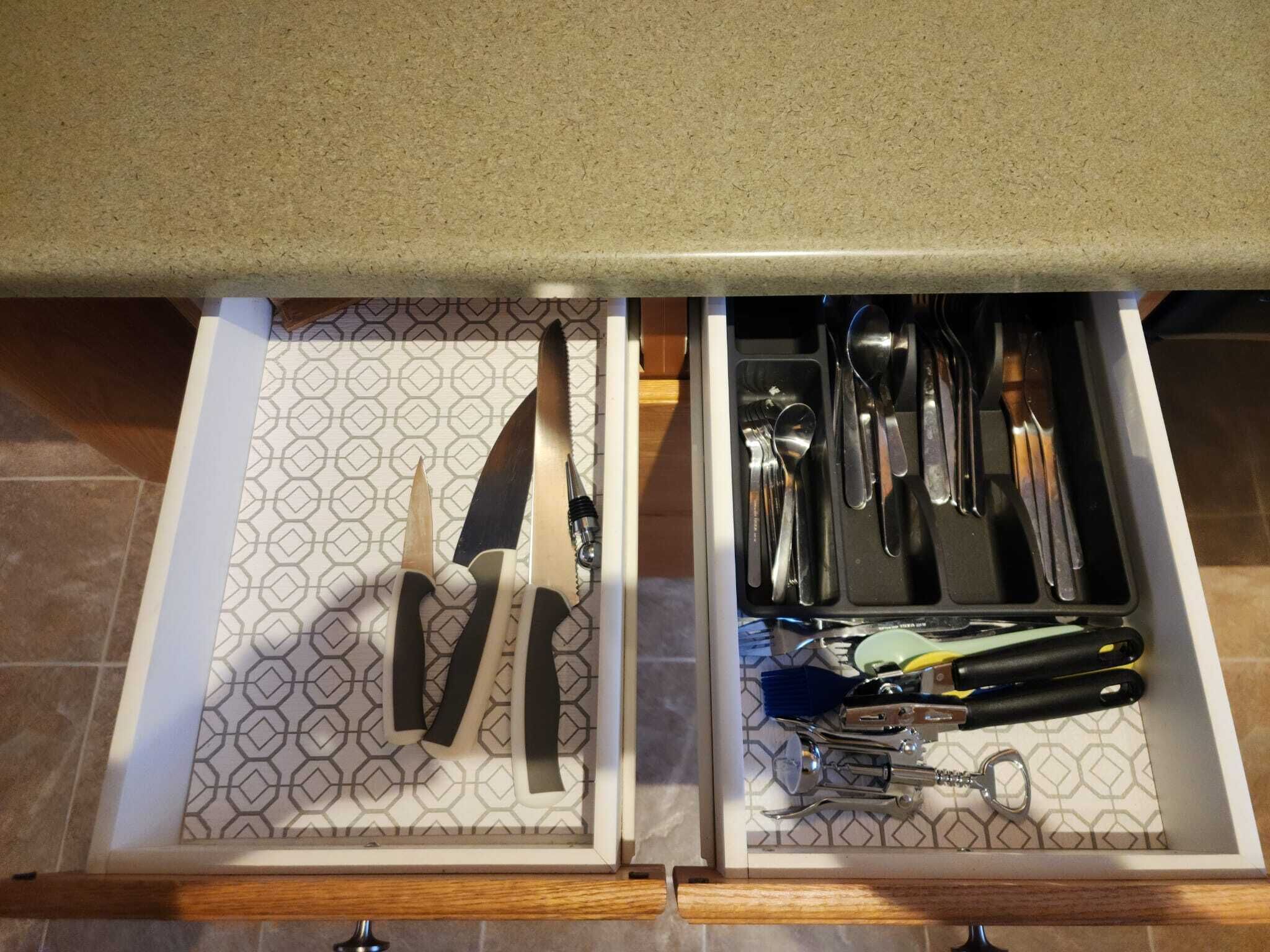 A drawer with utensils and a knife.