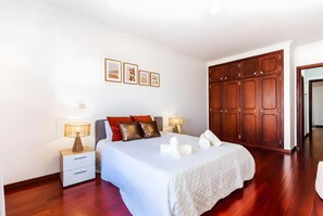 Une chambre à coucher avec un lit, des tables de chevet, une armoire et des tableaux encadrés accrochés au mur.