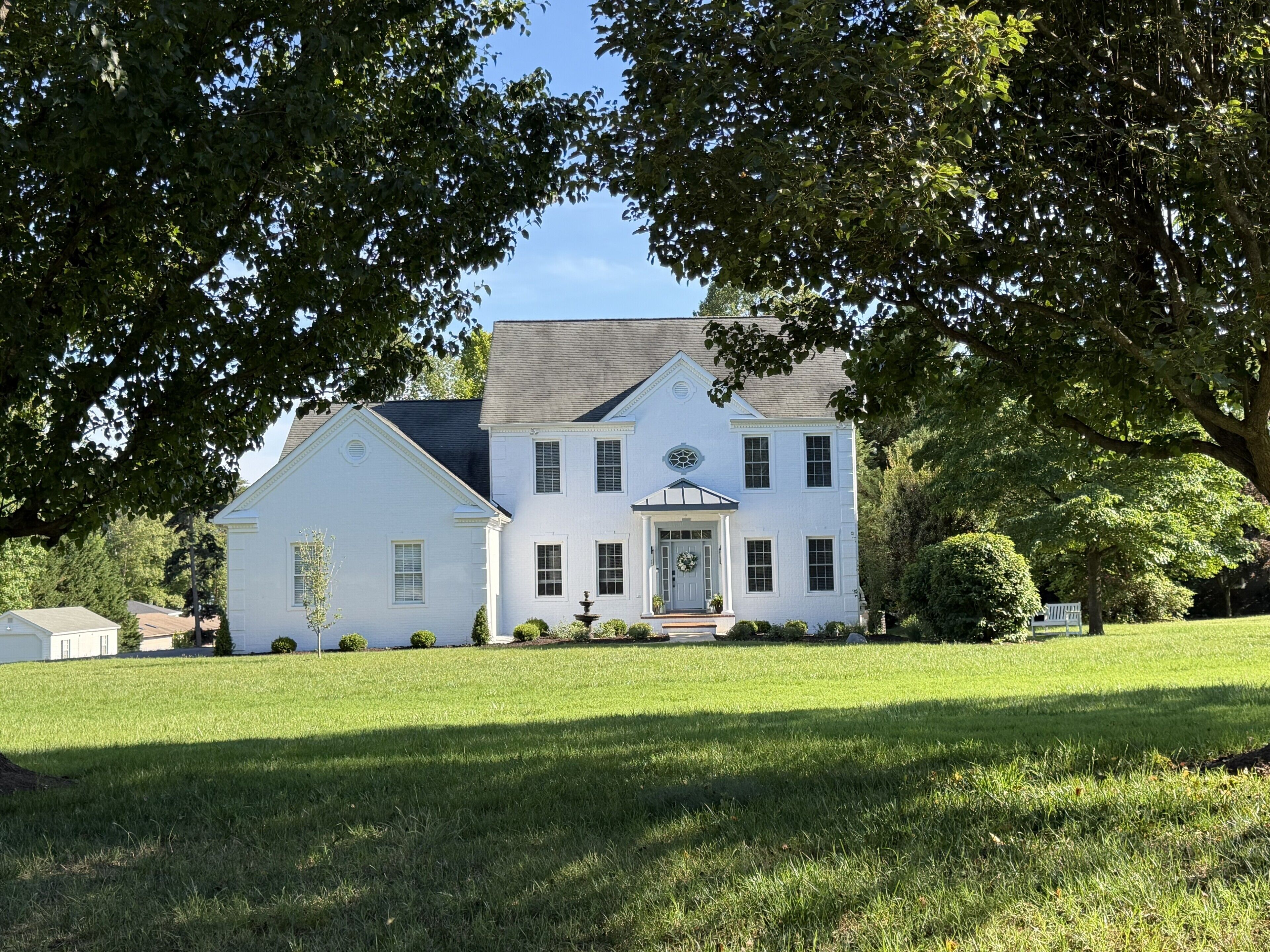 A large white house with a front porch, a chimney, and a well-maintained lawn.