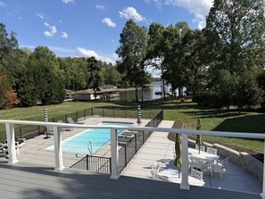 A deck with a pool, outdoor furniture, and a view of a lake and dock.