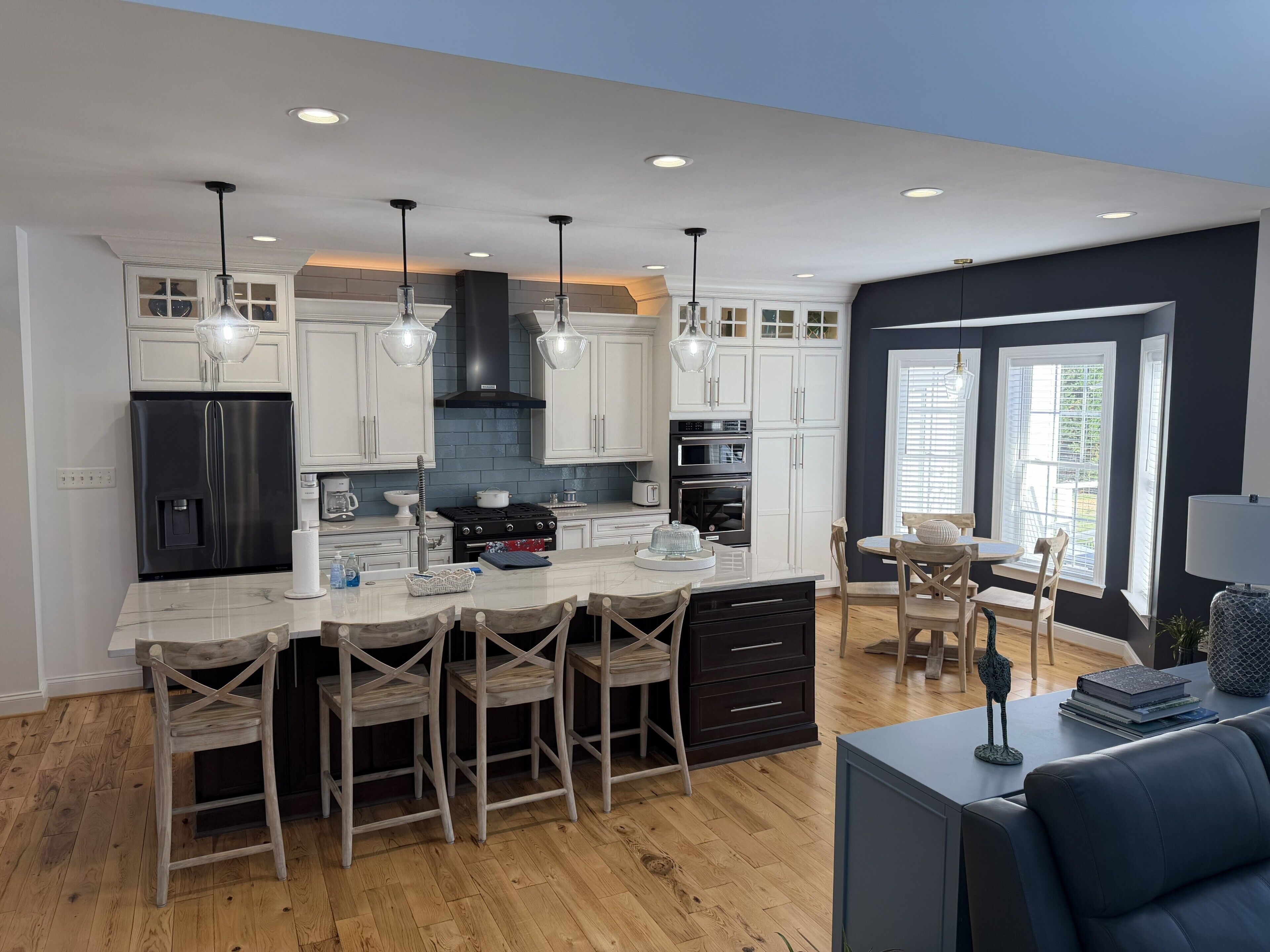 Una cocina moderna con armarios blancos, un refrigerador negro y una isla central con taburetes de bar.