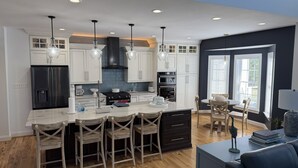 A modern kitchen with white cabinets, a black refrigerator, and a central island with bar stools.