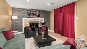 Ein Wohnzimmer mit Kamin, zwei Sofas, einem Couchtisch und einem roten Vorhang.