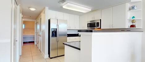 A modern kitchen with white cabinets, stainless steel appliances, and a central island.