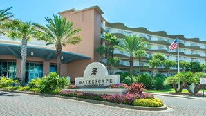 A hotel entrance with a sign reading "WATERSCAPE 1100 Santa Rosa Blvd." surrounded by palm trees and flowers. - Waterscape 424-b (Fort Walton Beach)