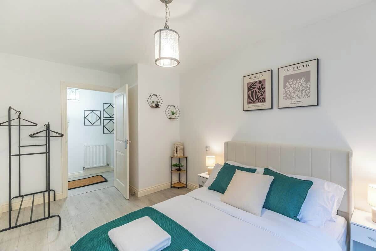 Een moderne hotelkamer met een net opgemaakt bed, een hanglamp en twee ingekaderde foto's aan de muur.
