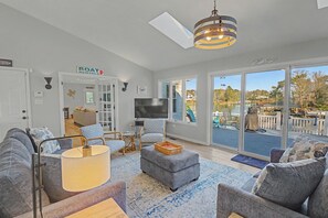 A spacious living room with a large TV, comfortable seating, and a view of the outdoors. - Peaceful home with dock, kayaks and sunset views (Deltaville)