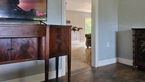 A living room with a wooden cabinet, a television displaying 'The Michael Knowles Show', and a door leading to another room.