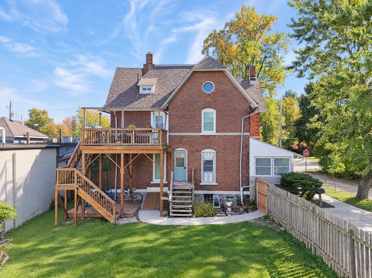 A two-story brick house with a wooden deck, a front door, and a small porch.