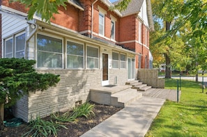 A two-story brick house with a front porch, a small garden, and a wooden fence.