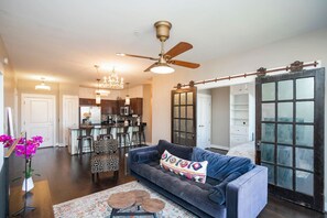 A modern living room with a sofa, a coffee table, and a chandelier. - Beautiful Condo in the Heart of Downtown Nashville (Nashville)