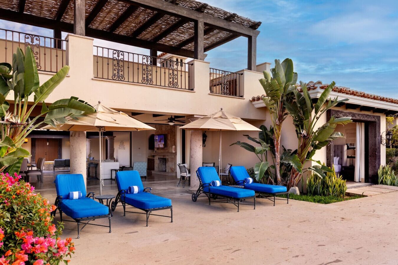 Un hôtel doté d’un espace extérieur couvert avec des sièges, de plusieurs fauteuils et d’une piscine.