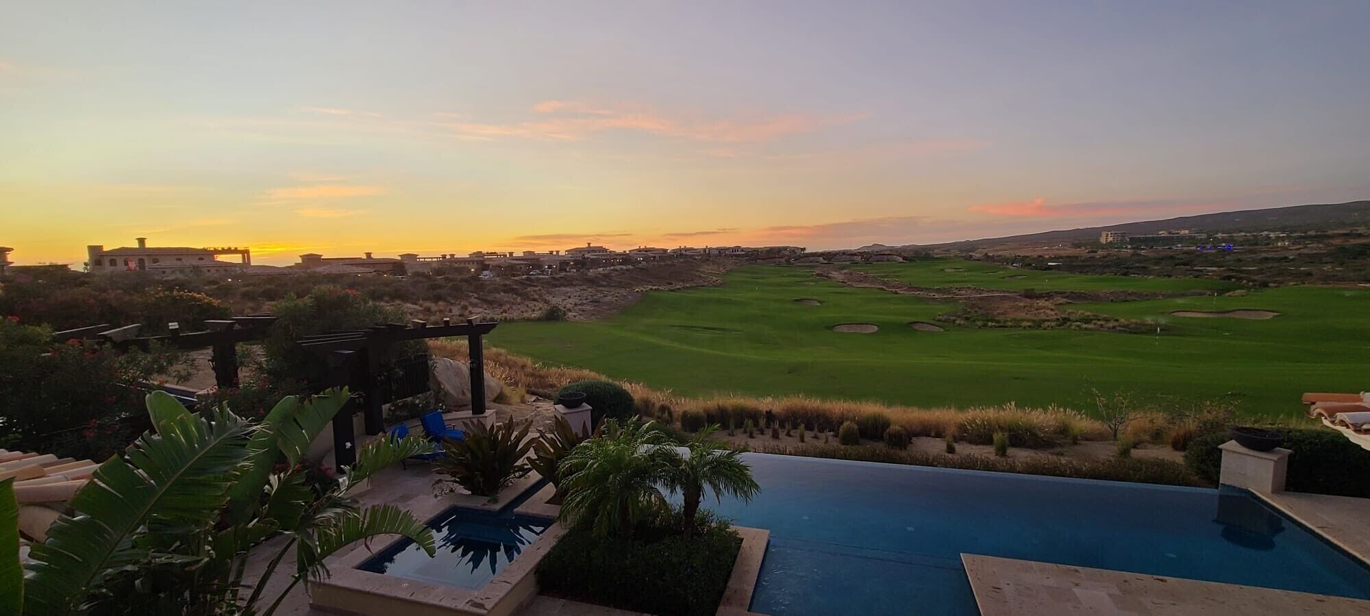 Un resort con piscina, campo de golf y vistas al atardecer.