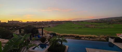 Un resort con piscina, campo de golf y vistas al atardecer.