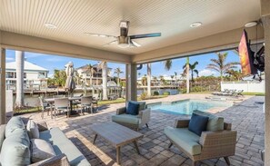 A covered outdoor area with a pool, lounge chairs, and dining tables. - Intracoastal Waterway Paradise (Fort Myers Beach)