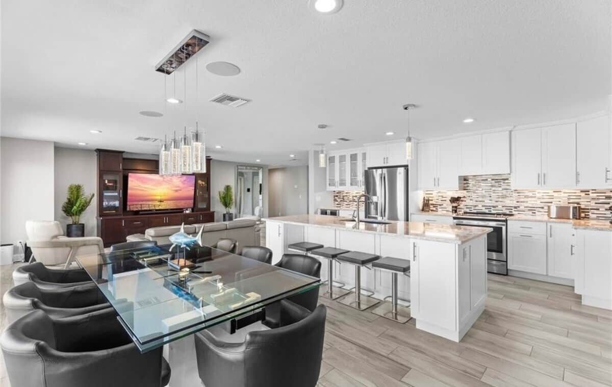 Una cocina moderna con gabinetes blancos, una isla central y electrodomésticos de acero inoxidable.