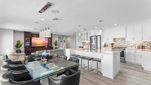 Une cuisine moderne avec des meubles blancs, un îlot central et des appareils électroménagers en acier inoxydable.