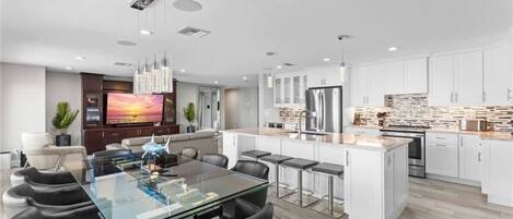 A modern kitchen with white cabinets, a central island, and stainless steel appliances.