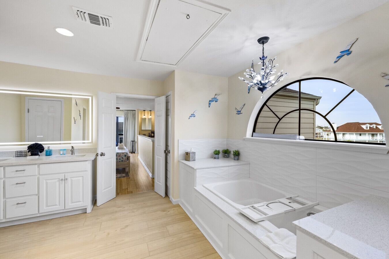 A modern bathroom with a large bathtub, a vanity with a mirror, and a window with a view of the outside.