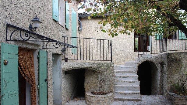 A stone staircase leading to a building with a metal railing and a small tree in a stone planter. - Village house Entrechaux (Entrechaux)